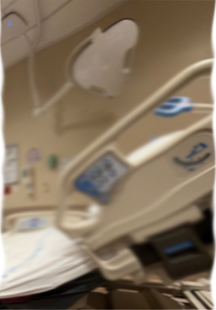 A blurred photo of a lamp and bed headrest